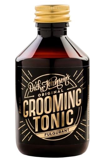 En liten mörk flaska med svart och guld etikett för Grooming Tonic, en hårvårdsprodukt. Flaskans lock är guld.