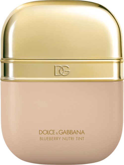 A small, round cosmetic container with a shiny gold top and light pink bottom, labeled Dolce & Gabbana Blueberry Nutri Tint.