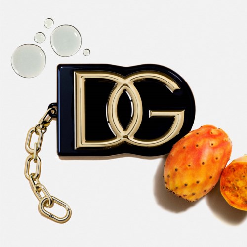 En Dolce & Gabbana-logo nøglering med orange kaktusfrugter og et par vanddråber på en hvid baggrund.