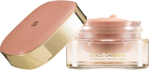 En rund kosmetisk burk i rosa och guld med matchande lock, märkt "DOLCE & GABBANA GLOW-BOUNCE CERAMIDE CREAM."