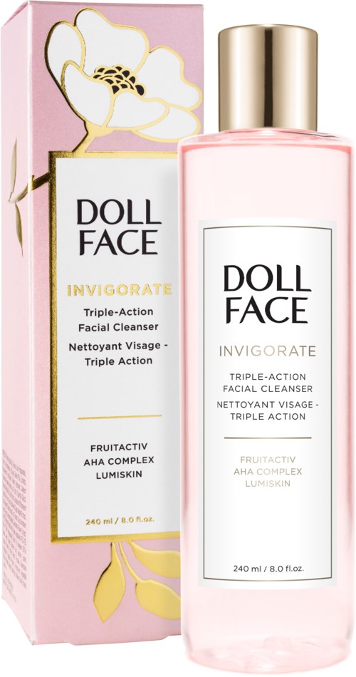 En rosa eske og en gjennomsiktig flaske med ansiktsrenser med gulltopper, merket "DOLL FACE INVIGORATE," med blomsterdesign.
