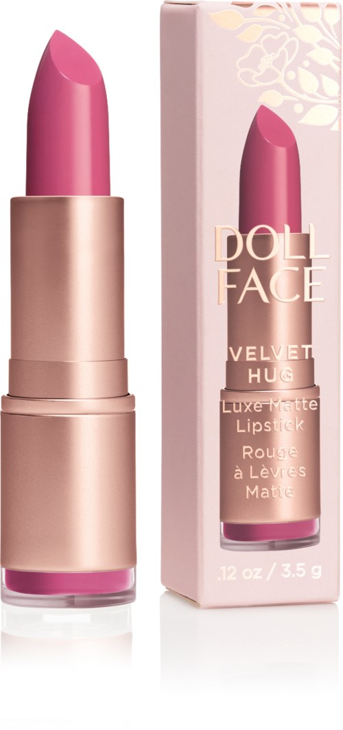 En rosa leppestift i et gullfarget deksel ved siden av en rosa eske med hvit og gull tekst. Esken viser produktdetaljer.