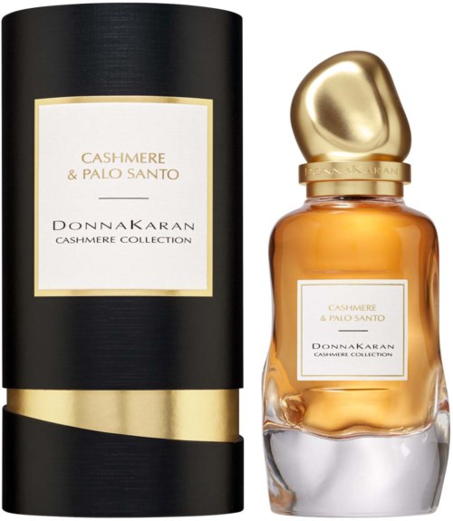 A perfume bottle with a golden cap and label, next to a tall black and gold cylindrical box. Both are from Cashmere & Palo Santo.