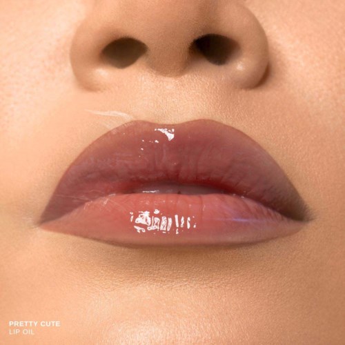 Close-up of lips with glossy, natural-colored lipstick and slight sheen. Nose is also visible.
