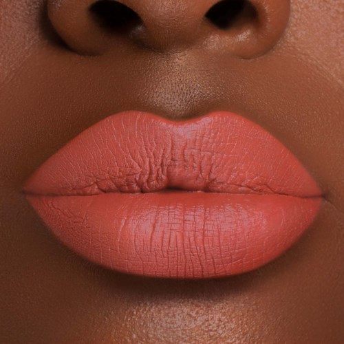 Close-up of full lips with peachy lipstick and smooth skin. Nostrils visible at the top of the image.