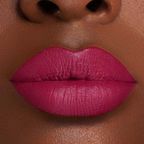 Close-up of lips with bright pink lipstick. The skin around is smooth and dark.