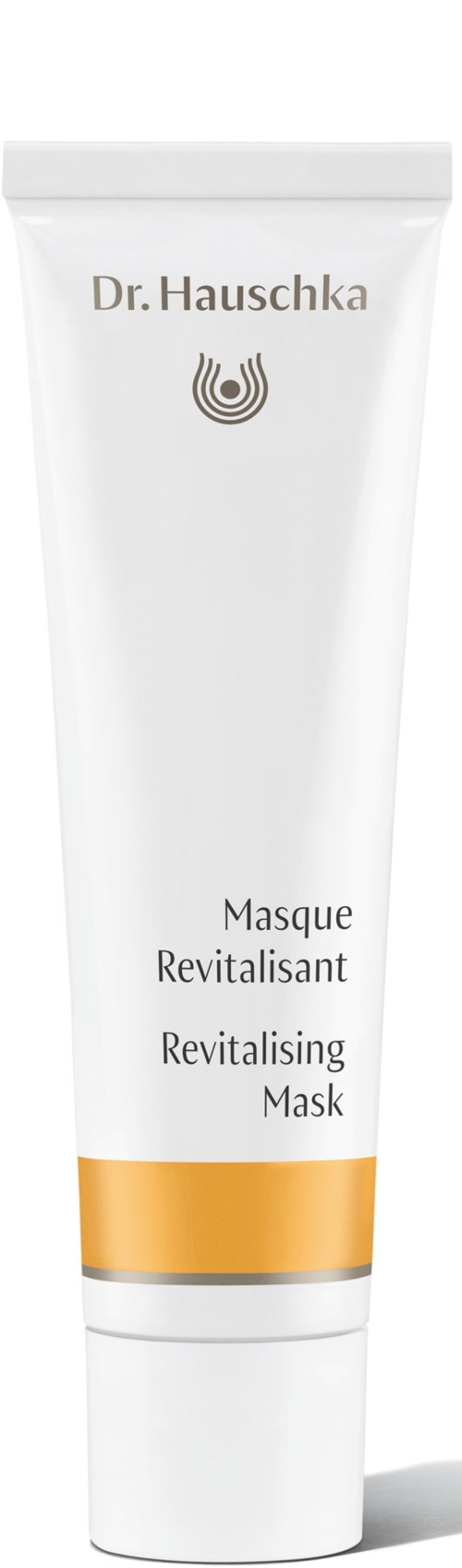 Valkoinen putkilo kultaisella nauhalla, jossa lukee Dr. Hauschka Revitalising Mask, seisoo pystyssä.