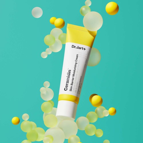 A tube of Dr. Jart+ Ceramidin skin barrier moisturizing cream surrounded by colorful spheres.