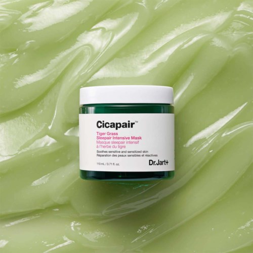 Bilden visar en grön burk med Dr. Jart+ Cicapair Tiger Grass Sleep Mask på en grön, geléliknande bakgrund.