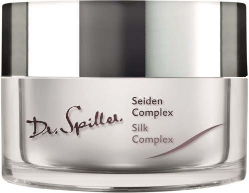 En hudpleieboks merket 'Dr. Spiller Seiden Complex Silk Complex' med lokk i sølv. Boksen er gjennomsiktig som viser krem inni.