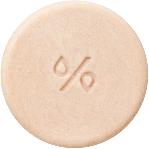 Det är en rund, beige tablett med en procent-symbol, troligen medicin eller vitamintablett.
