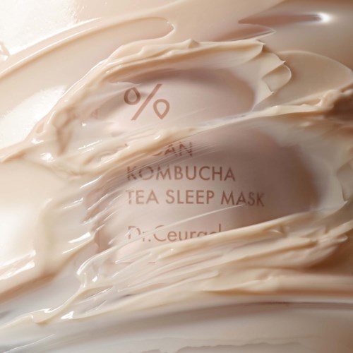Ein cremefarbenes Produkt mit Text, der 'KOMBUCHA TEA SLEEP MASK' sagt, teilweise bedeckt.