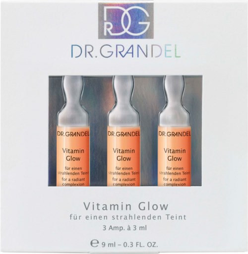 Tre små flaskor märkta 'Vitamin Glow' syns inuti en box, avsedda för strålande hud. Boxen har en märkeslogga och namn.