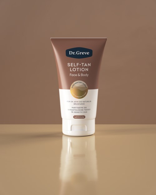 En brunt och vit tub märkt 'Dr. Greve Self-Tan Lotion' står upprätt på en beige yta mot en enkel bakgrund.