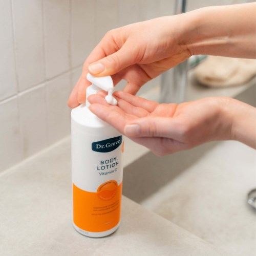 En person bruger en pumpeflaske med body lotion mærket Dr. Greve med vitamin C.