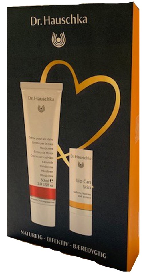 Box med Dr. Hauschka hudvårdsprodukter, inklusive läppvårdstift, på svart bakgrund med en guldhjärtlinje.