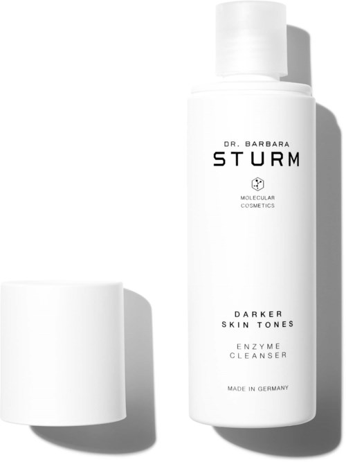 En hvit flaske merket 'Dr. Barbara Sturm Darker Skin Tones Enzyme Cleanser' med et separat lokk til venstre.