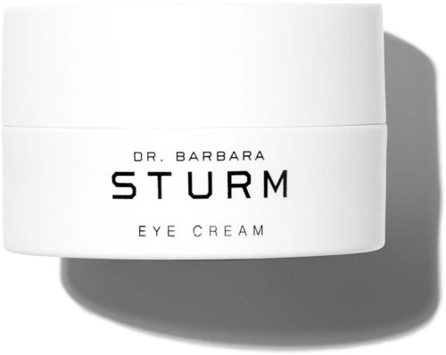 En vit burk med ögonkräm med svart text, märkt 'Dr. Barbara Sturm Eye Cream,' kastar en skugga.