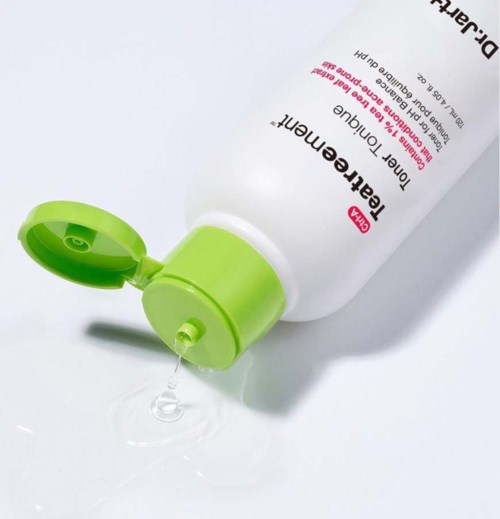 En vit tub med första hjälpen-lotion med ett grönt lock som är lätt öppnat, med gel som kommer ut på en vit yta.