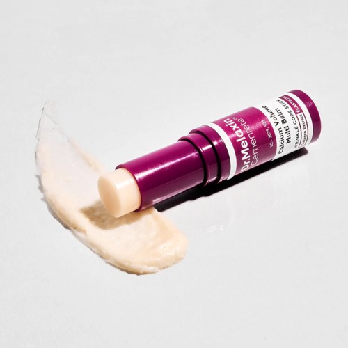 Lippenbalsemtube met witte balsem en paarse verpakking. Het ligt op een witte ondergrond.