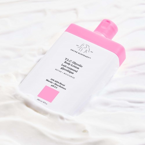 Pink och vit lotionflaska med rosa kork, placerad på en vit yta.