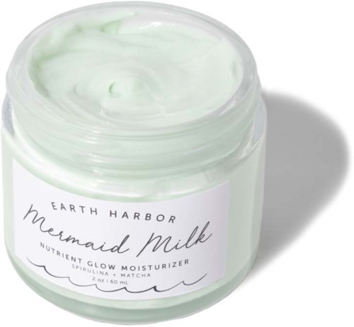 En burk med grön fuktighetskräm med vit etikett som lyder 'Earth Harbor Mermaid Milk' och innehåller växtbaserade ingredienser.