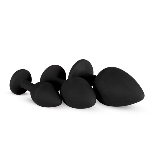 A set of black massage stones of different sizes arranged on a white surface.