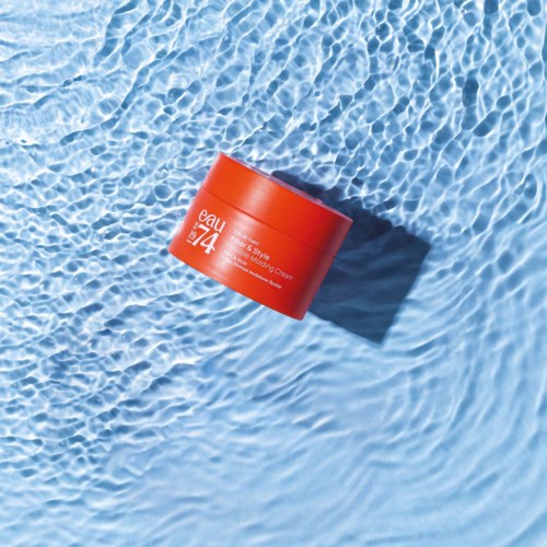 A red round container floats in a swimming pool, casting a shadow on the water.