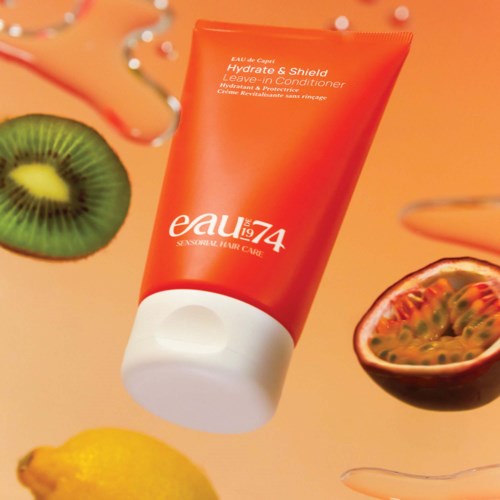 A red tube labeled 'eau' with fruit slices like kiwi, lemon, and passion fruit around it.