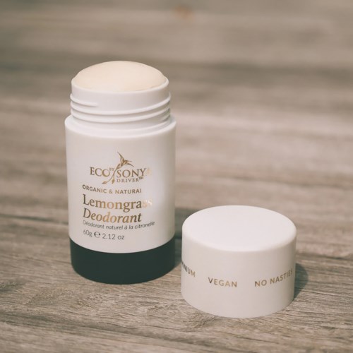 A white deodorant stick container with a removable lid, labeled eco-friendly lemon-grass deodorant, on a wooden surface.