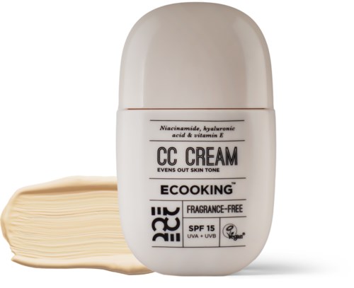 En lille flaske mærket 'CC Cream' med beige farve, og lidt creme udpresset ved siden af.