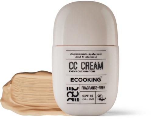 En hvid flaske CC-cream med en beige prøve ved siden af, mærket som miljøvenlig, SPF 15 og duftfri.