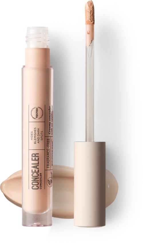 Concealer-rør med påføringsspids, beige væske spildt ved siden af, på hvid baggrund.
