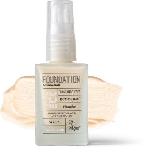 En flaske foundation med pumpe, mærket 'Vegan', 'Parfymfri', SPF 15 og indeholder vitaminer.