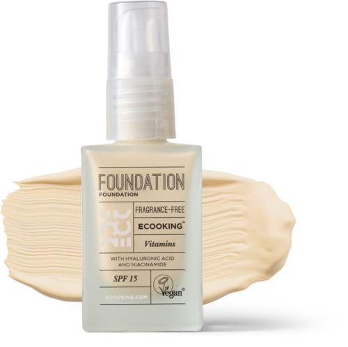 En flaske duftfri foundation med vitaminer, SPF 15, vegansk mærke og en cremet baggrund.