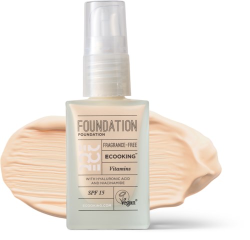 Vegan foundation-flaske med SPF 15, hyaluronsyre, niacinamide og parfymefri. Cremet er spredt bagved den.