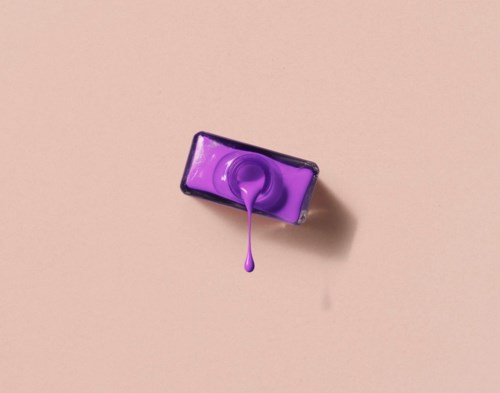 Purple nail polish bottle with the lid open and polish dripping.