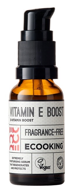 En ravfarvet flaske med sort pumpe, mærket 'Vitamin E Boost', 'Fragrance-Free', og 'EcoKing'. Det er en serumflaske.