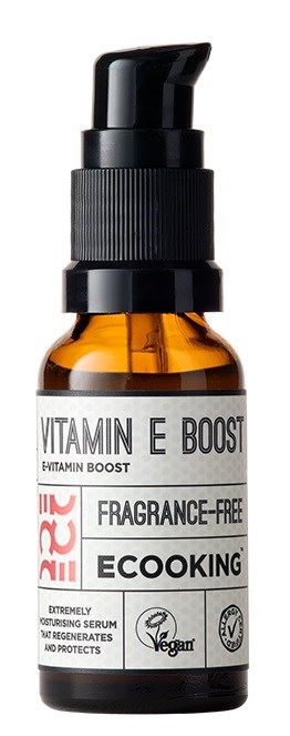Small amber bottle with black pump, labeled 'Vitamin E Boost' for skincare, fragrance-free, vegan, eco-friendly.