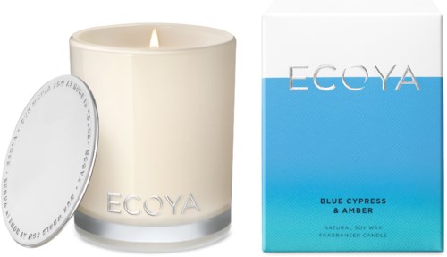 En vit doftljus med låga, och en låda och lock bredvid, märkt Ecoya, doften heter Blue Cypress & Amber.