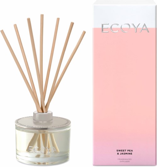 Ett glaskärl med träpinnar bredvid en rosa och vit box märkt EGYA, doftad av sötkäpe och jasmin.