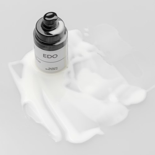 Een flesje met 'EDO' op witte crème of lotion met wat geknoeide substantie eromheen.