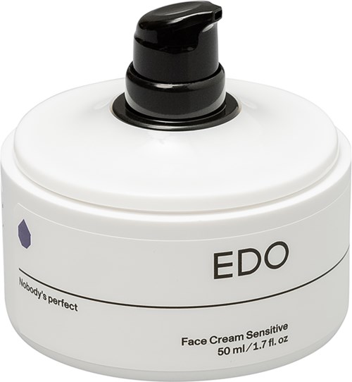 Een witte pot met Eddie gezichtscrème met zwarte pomp. Het is gemarkeerd als gevoelig en perfect voor het gezicht.