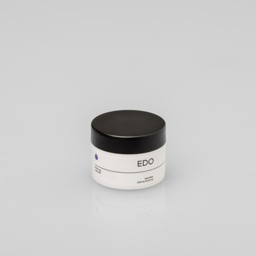 Een witte pot met zwarte deksel, gemarkeerd "EDO," op een lichtgrijze ondergrond.
