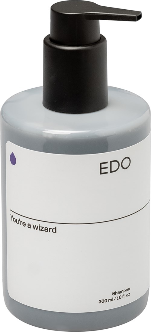 Een grijzige shampoo fles met een zwarte pomp en een simpel wit label dat zegt 'EDO' en 'You're a wizard.'