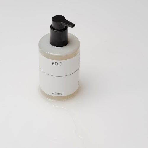 Een witte fles met een zwarte pomp met het label "EDO" staat op een witte oppervlakte.