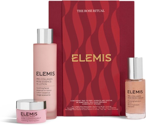 Et hudpleiesett med en rosa lotion, en liten krukke og en aprikosfarget serum foran en rød eske med gullfarget tekst.