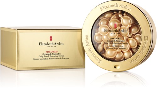 Sirkulær beholder med gullfargede kapsler inni og en eske ved siden av, begge merket Elizabeth Arden, inneholder hudpleiekapsler.