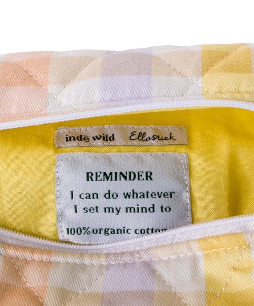A yellow bag with a reminder label about being positive and using organic cotton. The bag is partially open showing its interior.