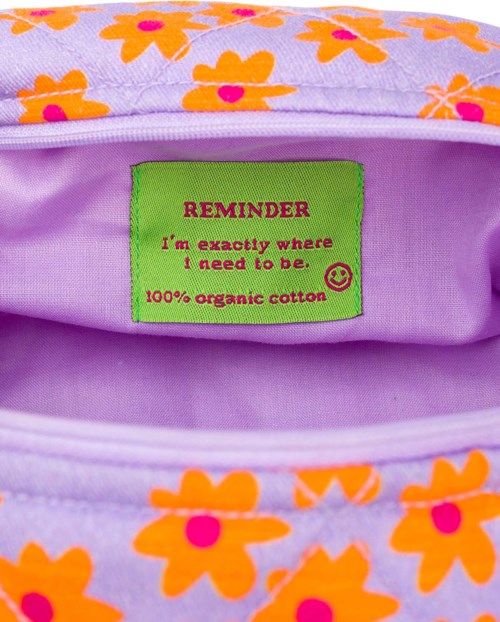 Bright floral fabric with a green tag stating: "REMINDER I'm exactly where I need to be. 100% organic cotton."